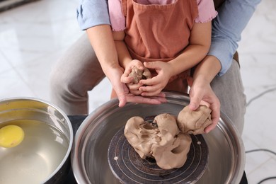 Photo of Hobby and craft. Mother with her daughter making pottery indoors, closeup