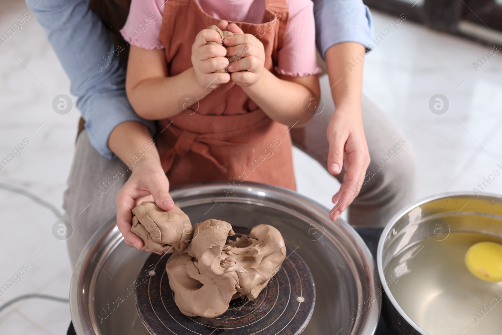 Photo of Hobby and craft. Mother with her daughter making pottery indoors, closeup