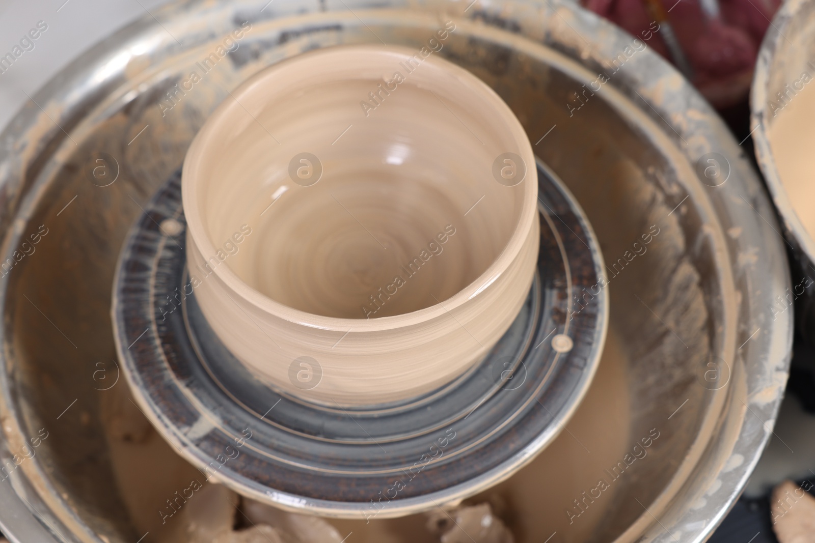 Photo of Hobby and craft. Beautiful bowl on potter's wheel in workshop, closeup