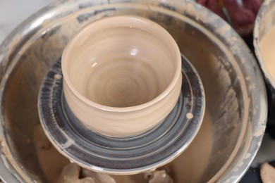 Photo of Hobby and craft. Beautiful bowl on potter's wheel in workshop, closeup