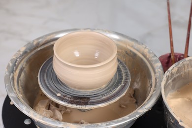 Photo of Hobby and craft. Beautiful bowl on potter's wheel in workshop, closeup