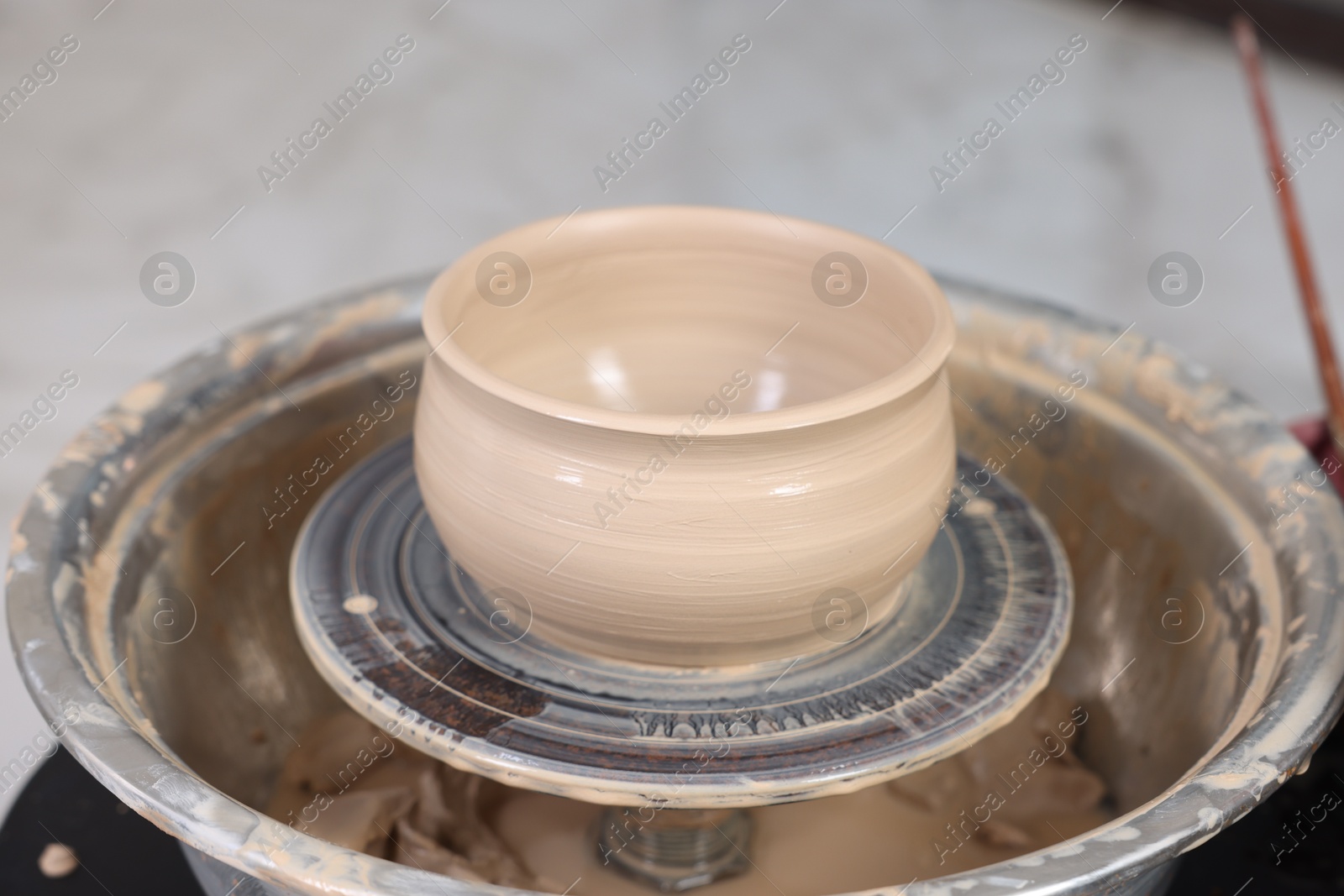 Photo of Hobby and craft. Beautiful bowl on potter's wheel in workshop, closeup