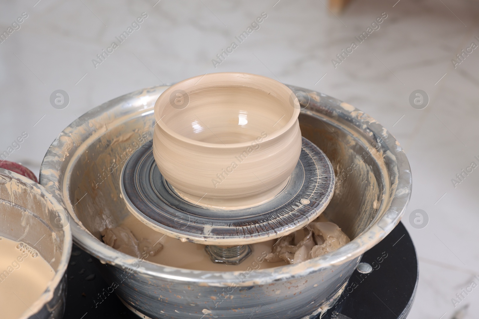 Photo of Hobby and craft. Beautiful bowl on potter's wheel in workshop, closeup