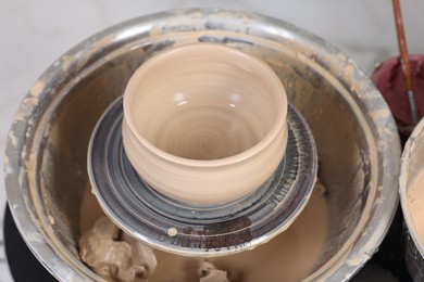 Photo of Hobby and craft. Beautiful bowl on potter's wheel in workshop, closeup