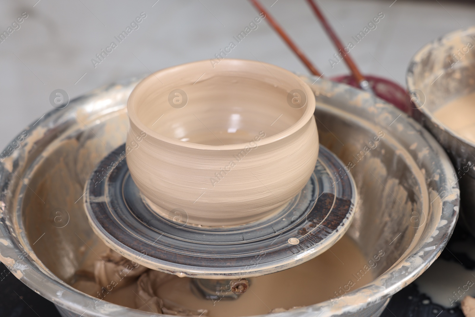 Photo of Hobby and craft. Beautiful bowl on potter's wheel in workshop, closeup