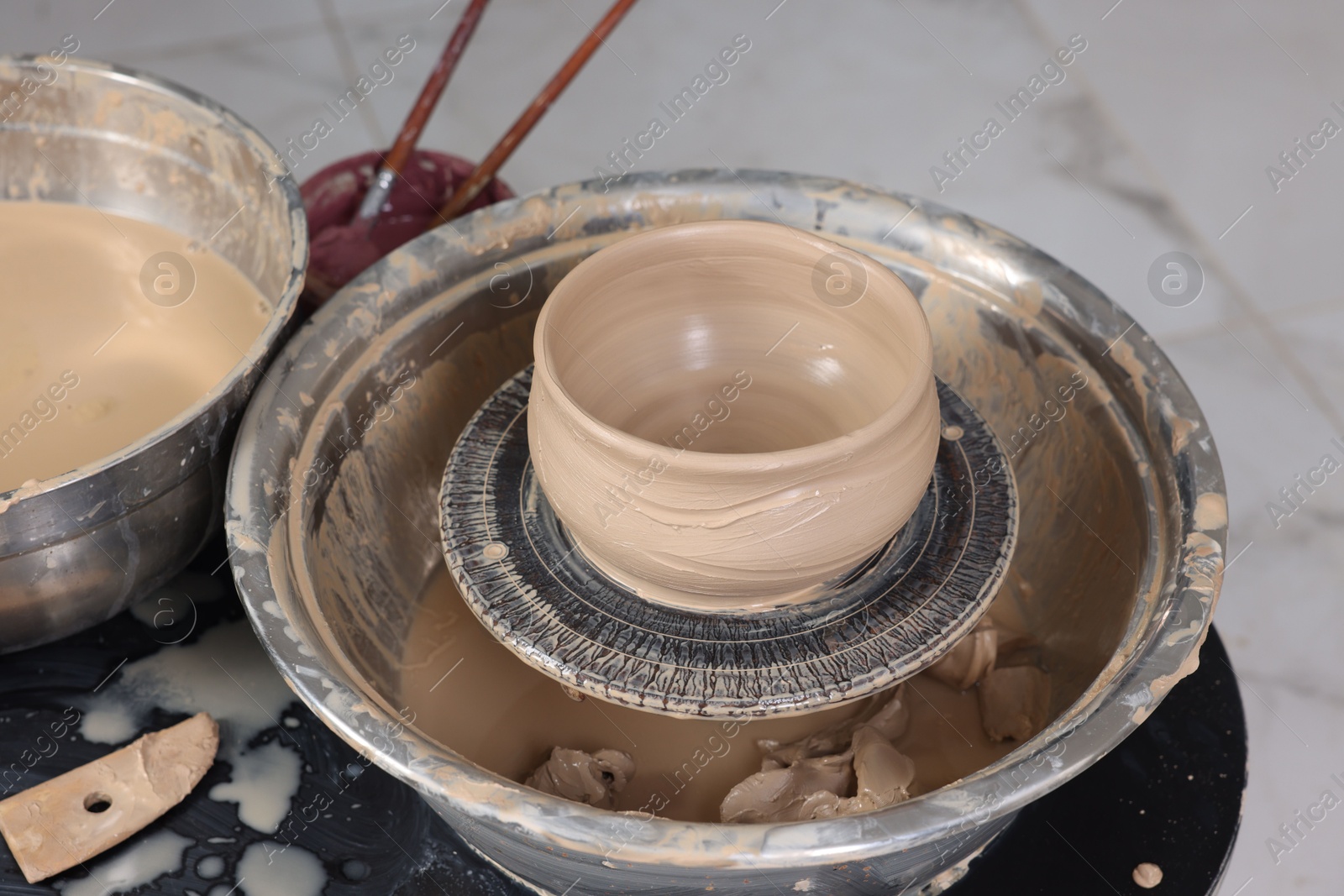 Photo of Hobby and craft. Beautiful bowl on potter's wheel in workshop, closeup