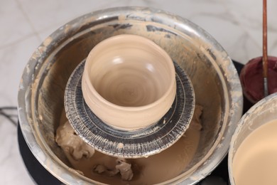 Photo of Hobby and craft. Beautiful bowl on potter's wheel in workshop, closeup