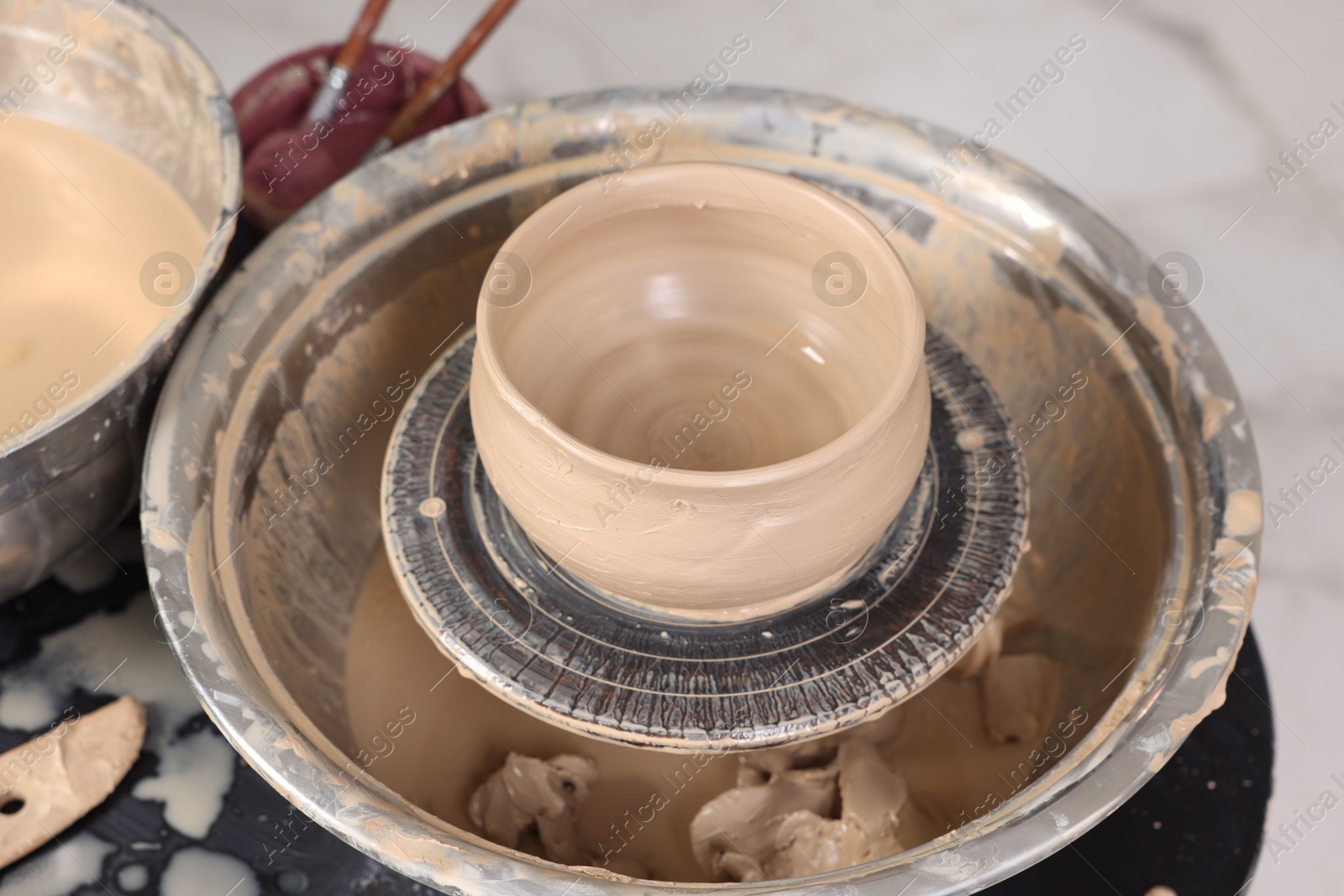 Photo of Hobby and craft. Beautiful bowl on potter's wheel in workshop, closeup