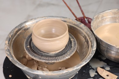 Photo of Hobby and craft. Beautiful bowl on potter's wheel in workshop, closeup