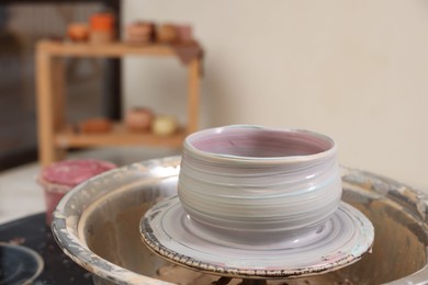 Photo of Hobby and craft. Beautiful bowl on potter's wheel in workshop, closeup