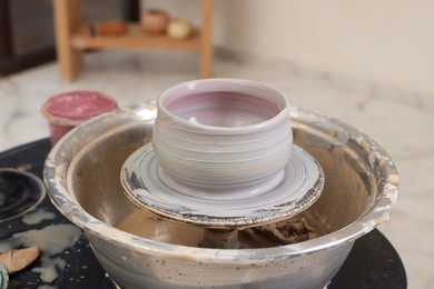 Photo of Hobby and craft. Beautiful bowl on potter's wheel in workshop, closeup