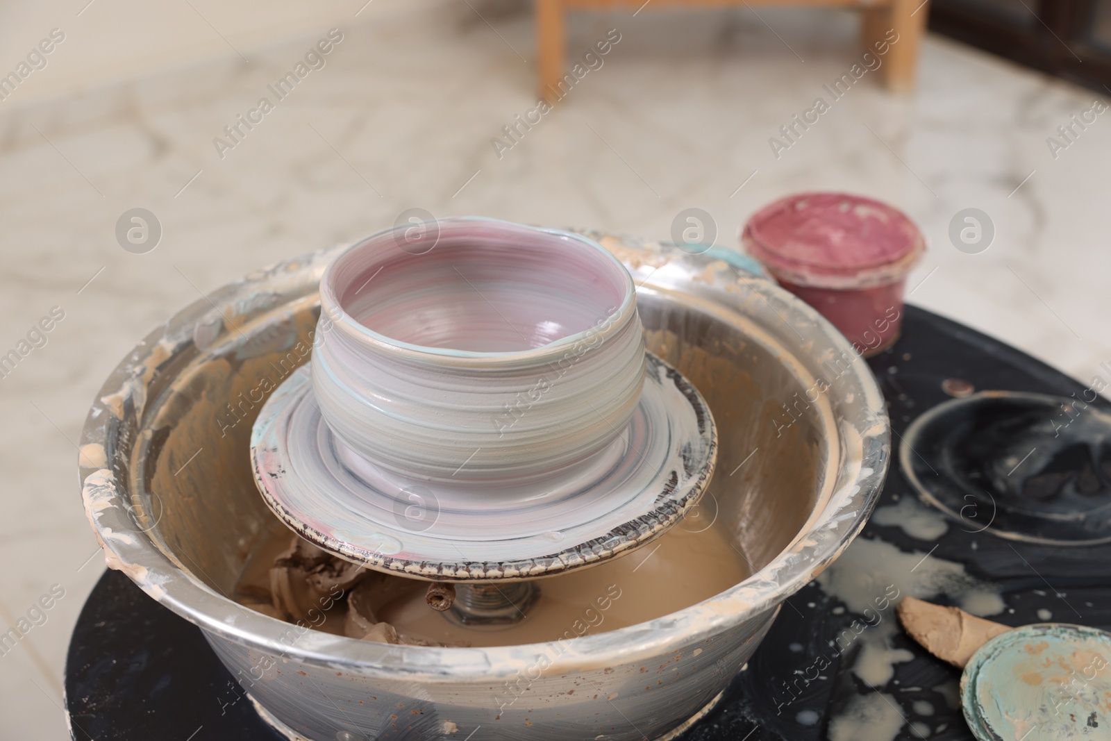 Photo of Hobby and craft. Beautiful bowl on potter's wheel in workshop, closeup