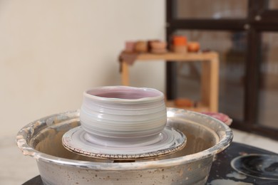 Photo of Hobby and craft. Beautiful bowl on potter's wheel in workshop, closeup