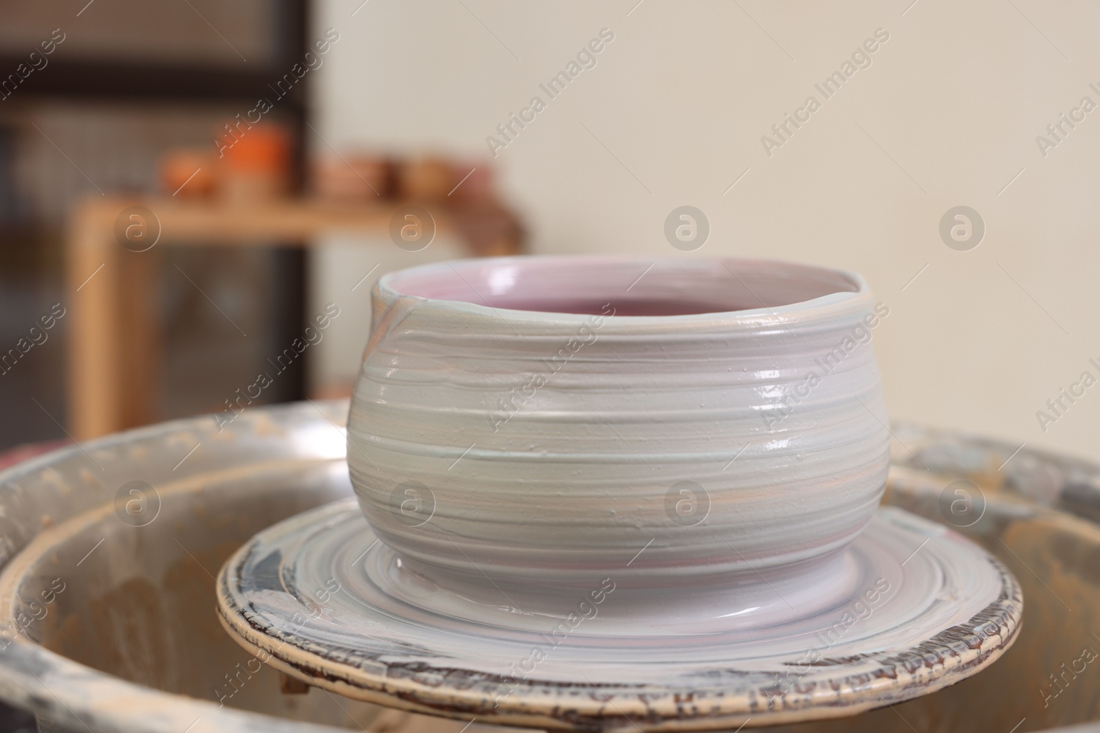 Photo of Hobby and craft. Beautiful bowl on potter's wheel in workshop, closeup