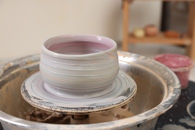 Photo of Hobby and craft. Beautiful bowl on potter's wheel in workshop, closeup