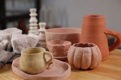 Photo of Hobby and craft. Different beautiful pottery on wooden table indoors, closeup