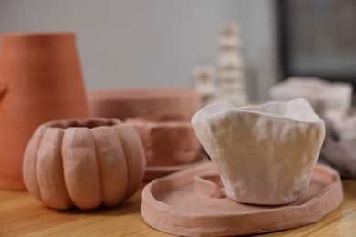 Photo of Hobby and craft. Different beautiful pottery on wooden table indoors, closeup