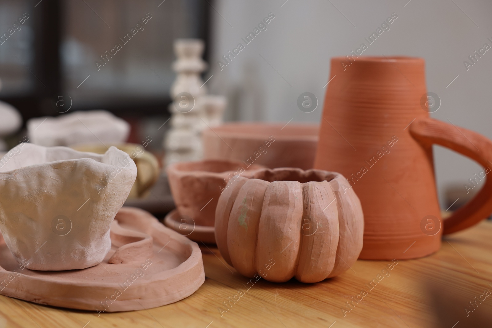 Photo of Hobby and craft. Different beautiful pottery on wooden table indoors, closeup