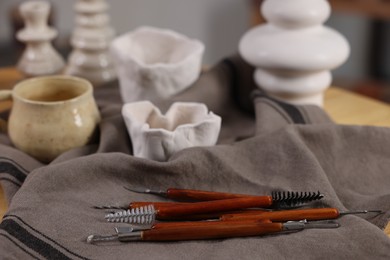 Photo of Set of different clay crafting tools and pottery on table, closeup