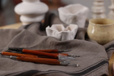 Photo of Set of different clay crafting tools and pottery on table, closeup