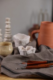 Photo of Set of different clay crafting tools and pottery on wooden table indoors, closeup