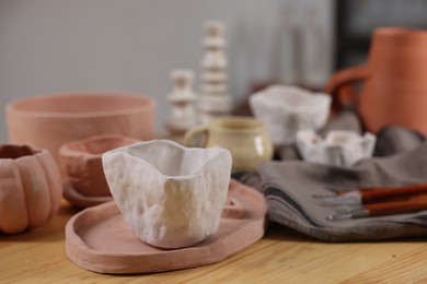 Photo of Hobby and craft. Different beautiful pottery on wooden table indoors, closeup