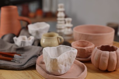 Photo of Hobby and craft. Different beautiful pottery on wooden table indoors, closeup