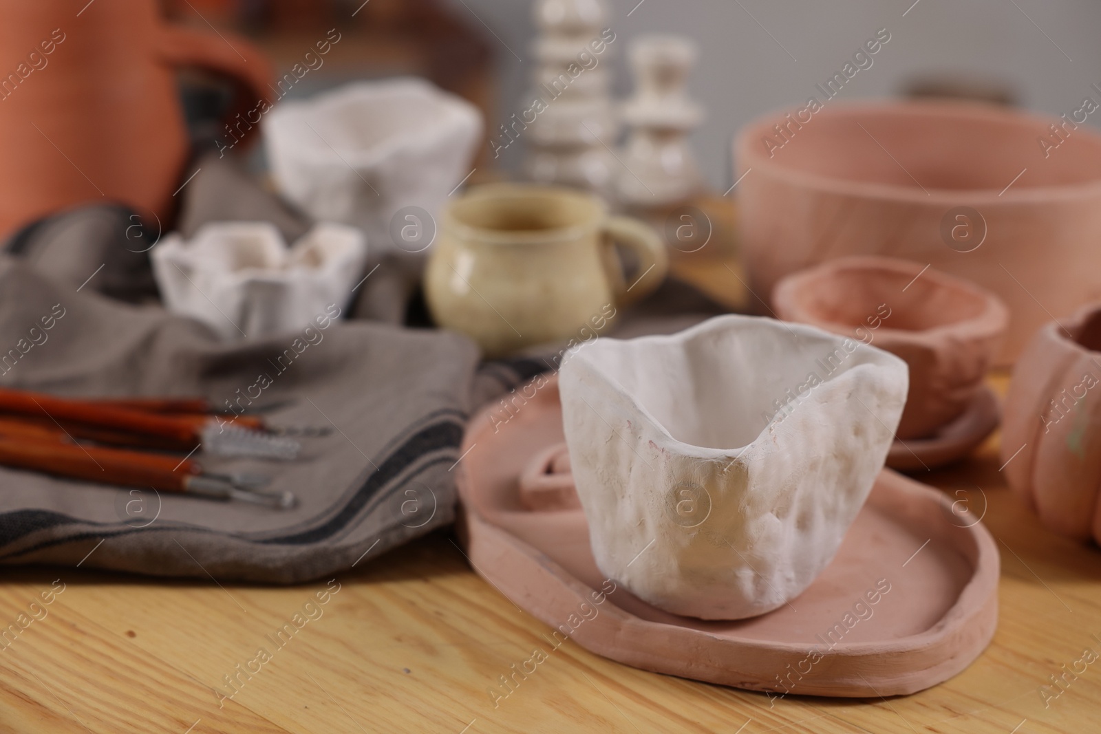 Photo of Hobby and craft. Different beautiful pottery on wooden table indoors, closeup