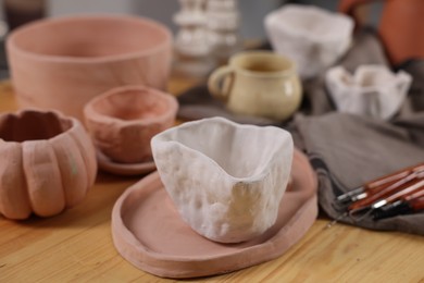 Photo of Hobby and craft. Different beautiful pottery on wooden table indoors, closeup