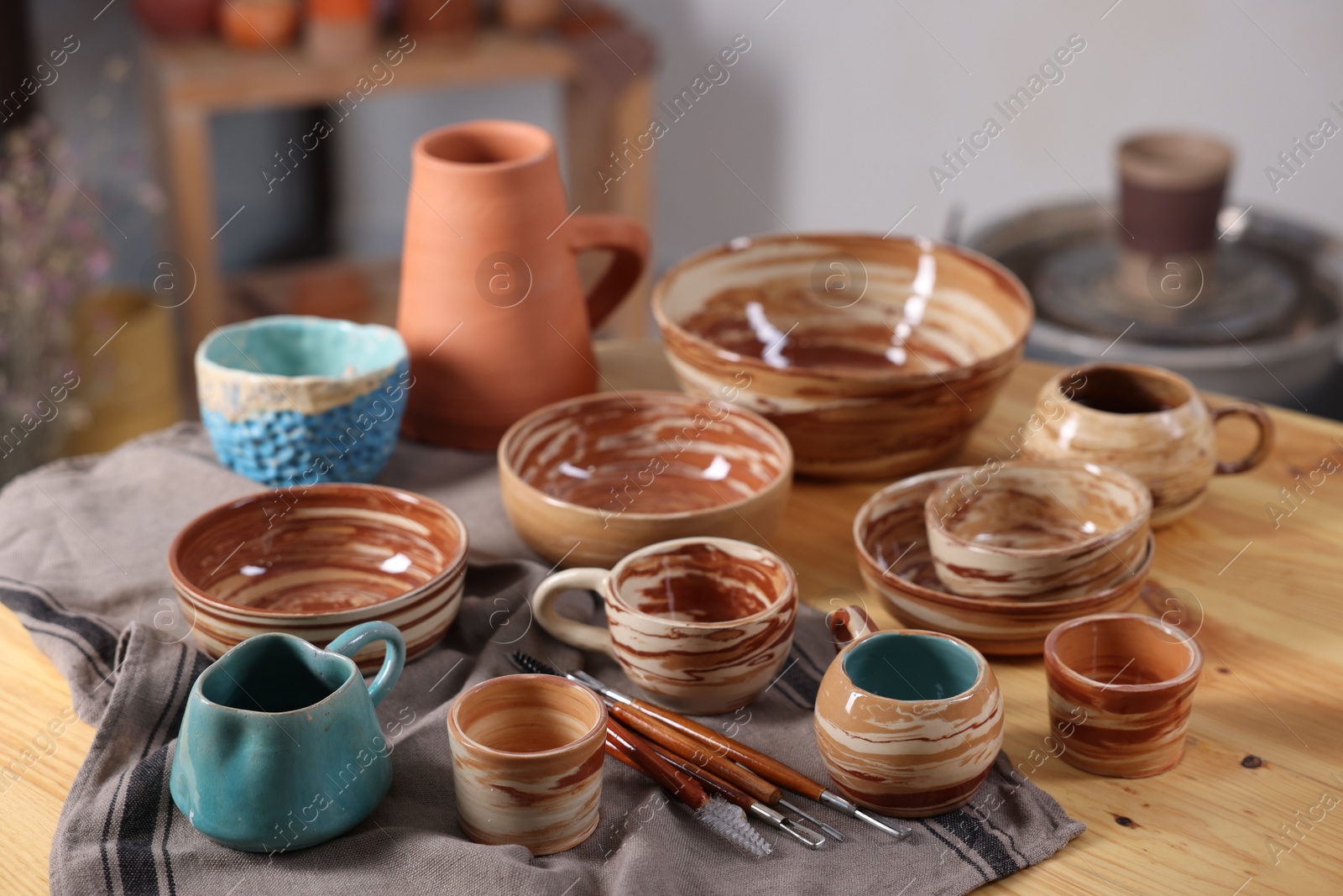 Photo of Different beautiful pottery and set of clay crafting tools on wooden table indoors