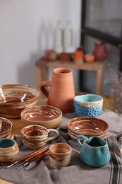 Photo of Different beautiful pottery and set of clay crafting tools on table indoors