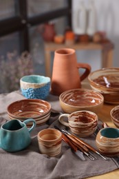 Photo of Different beautiful pottery and set of clay crafting tools on table indoors