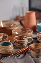 Photo of Different beautiful pottery and set of clay crafting tools on table indoors, closeup