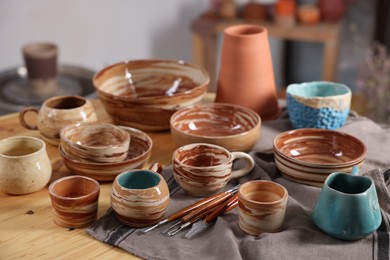 Photo of Different beautiful pottery and set of clay crafting tools on table indoors