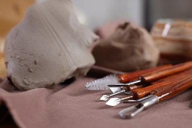 Photo of Set of different crafting tools and pieces of clay on table indoors, closeup