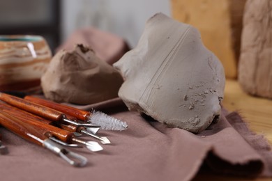 Photo of Set of different crafting tools and pieces of clay on table indoors, closeup