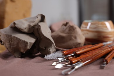 Photo of Set of different crafting tools and pieces of clay on table indoors, closeup