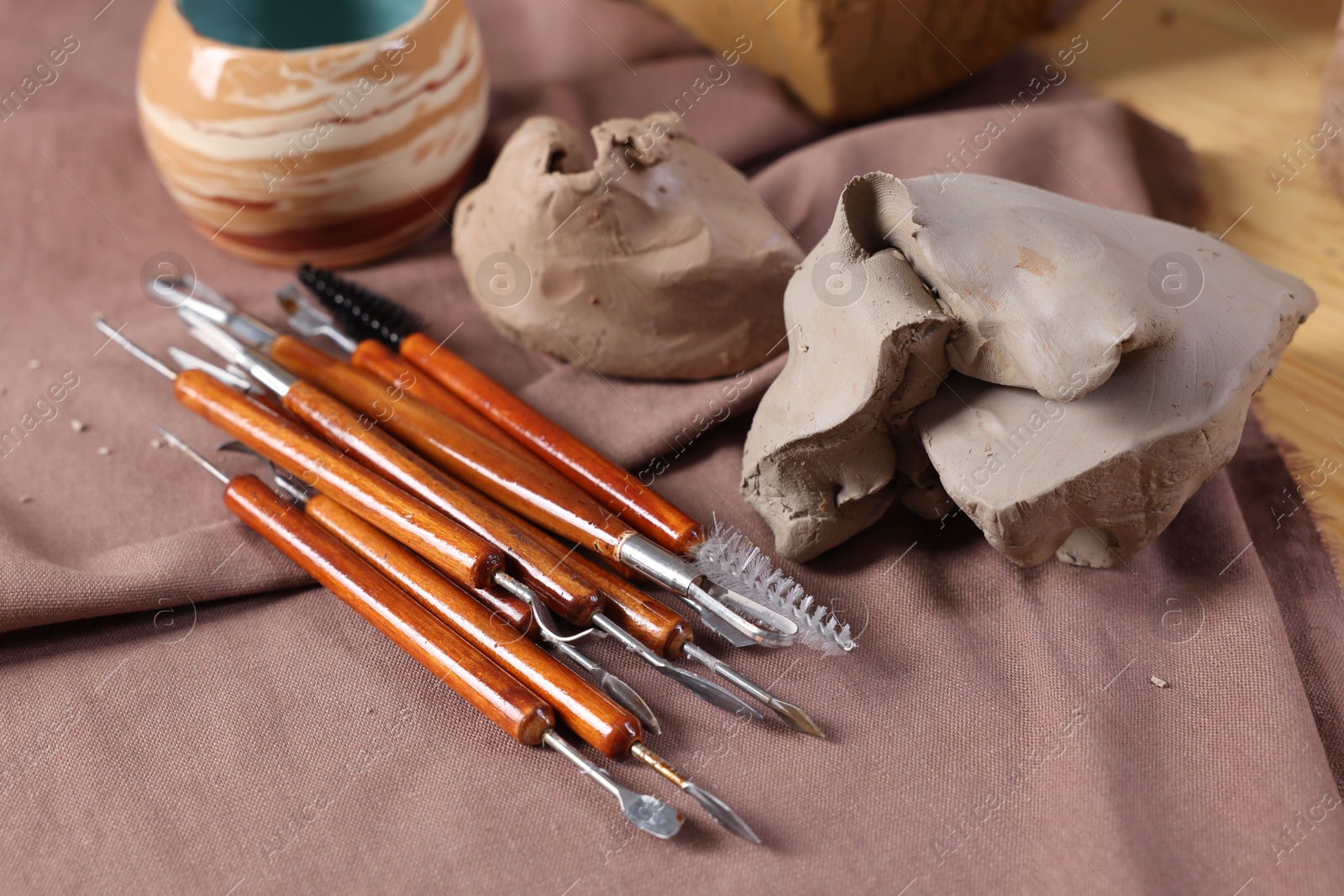 Photo of Set of different crafting tools and pieces of clay on table, closeup