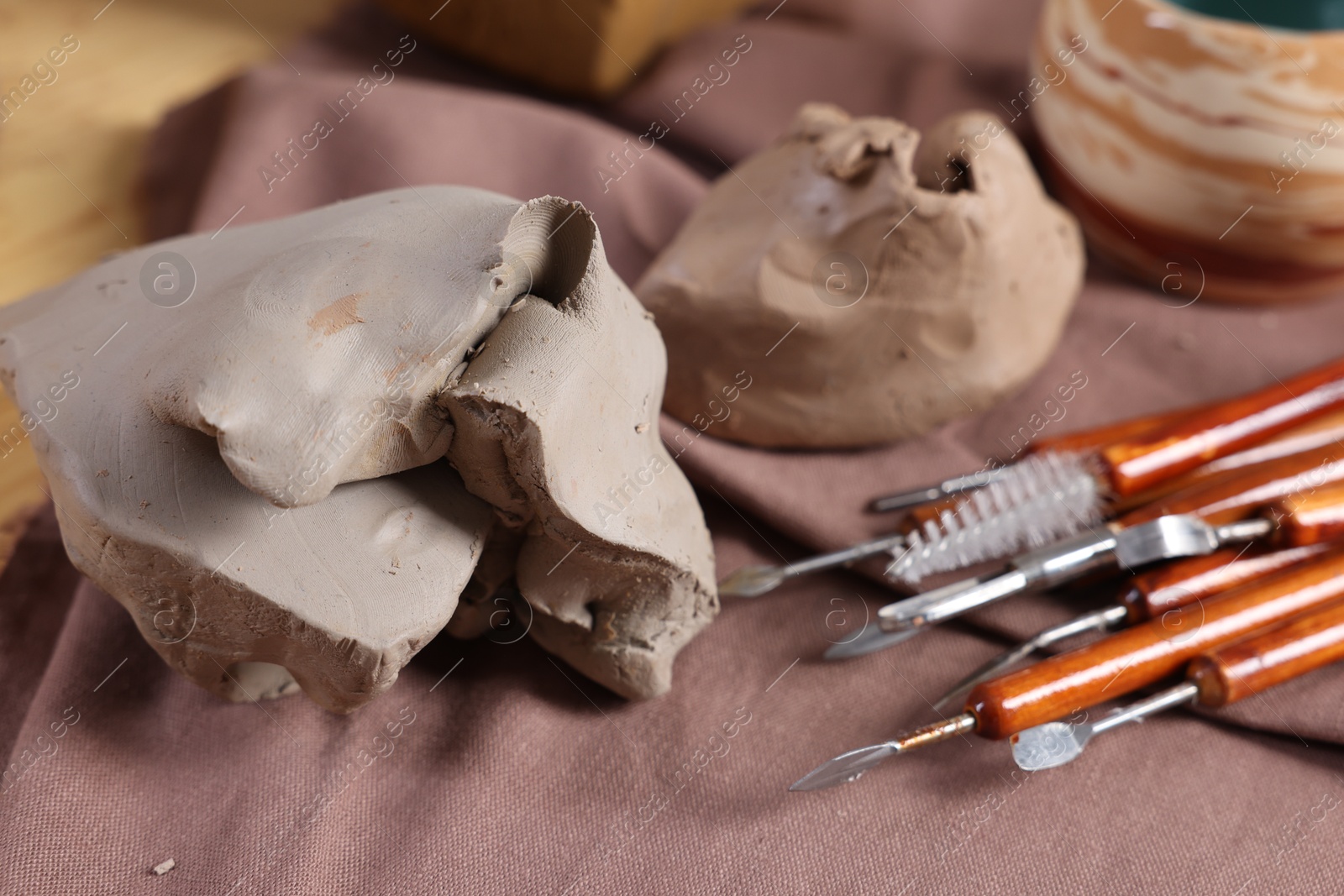 Photo of Set of different crafting tools and pieces of clay on table, closeup