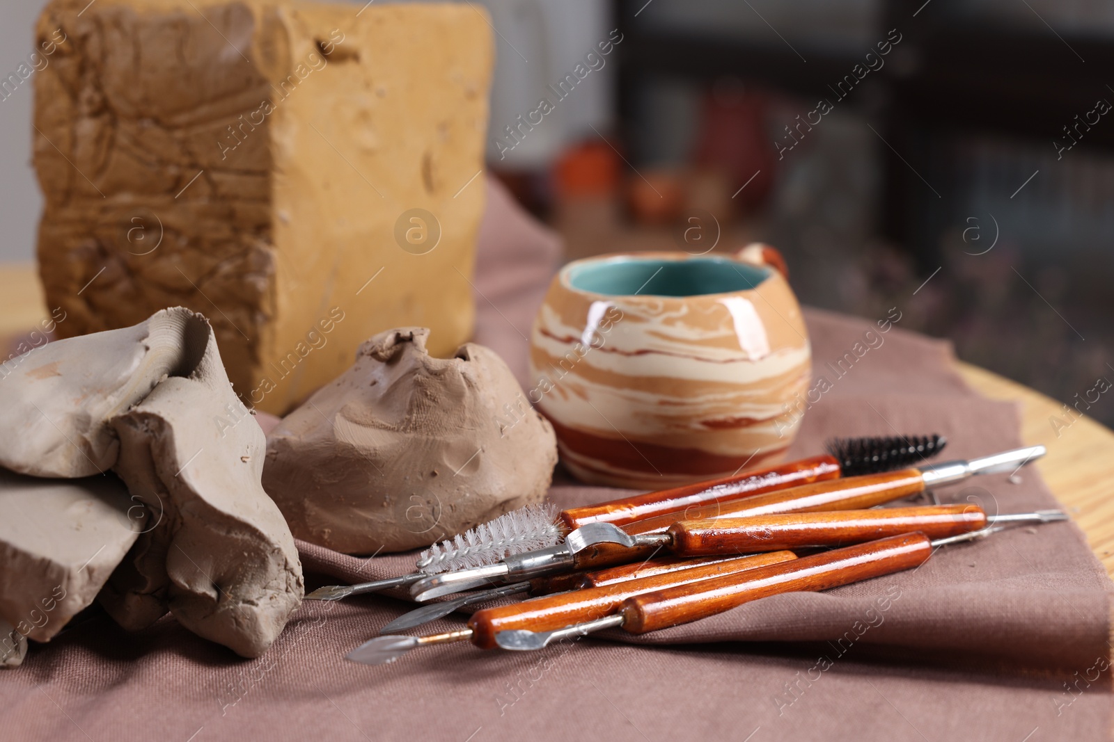 Photo of Set of different crafting tools and pieces of clay on table indoors, closeup