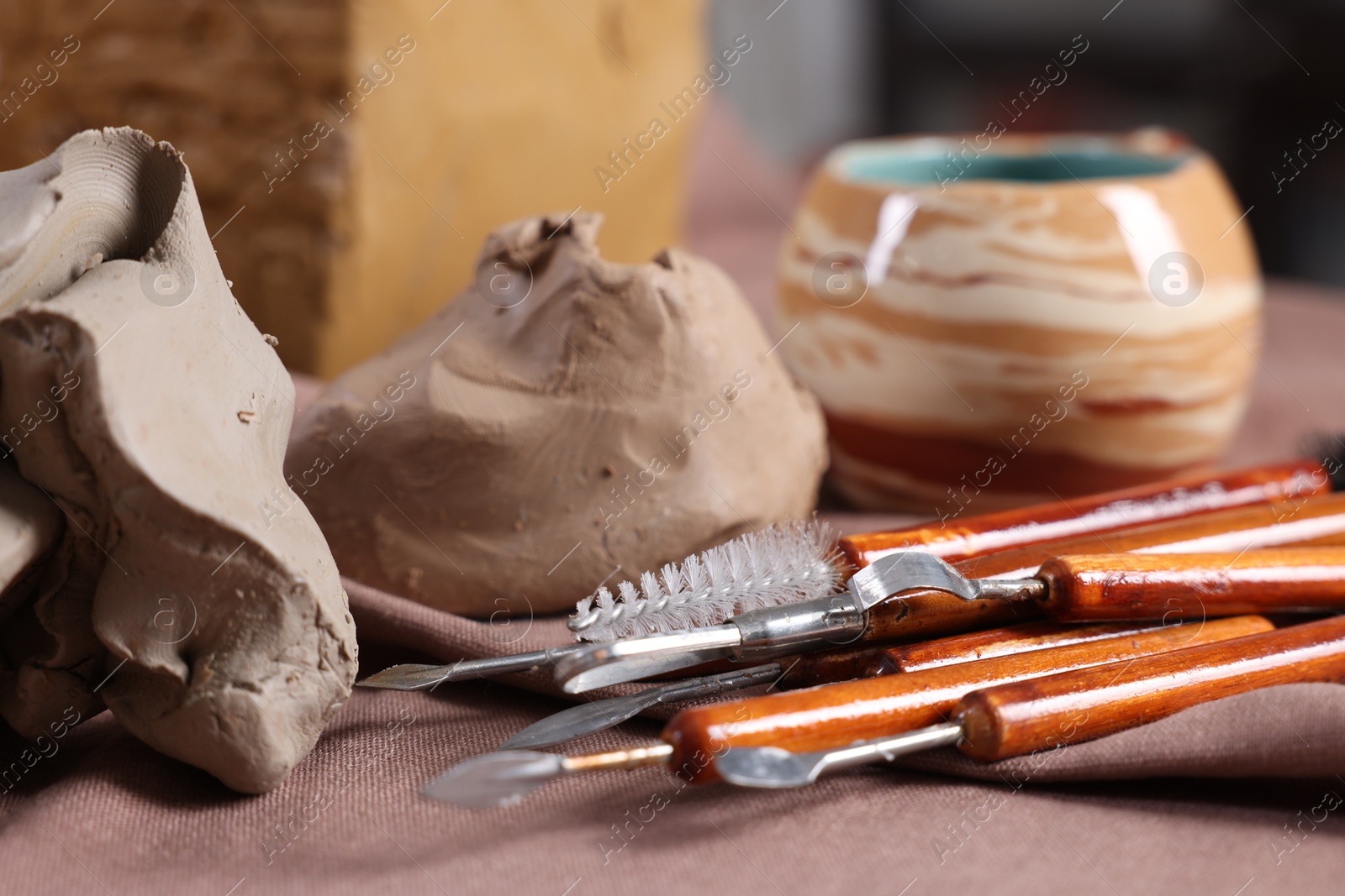 Photo of Set of different crafting tools and pieces of clay on table, closeup