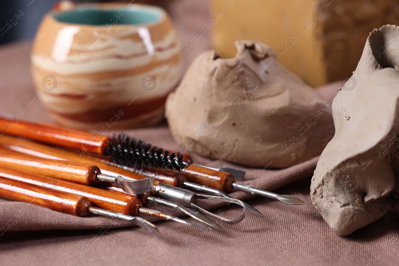 Photo of Set of different crafting tools and pieces of clay on table, closeup