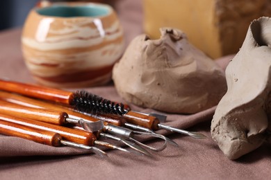 Photo of Set of different crafting tools and pieces of clay on table, closeup