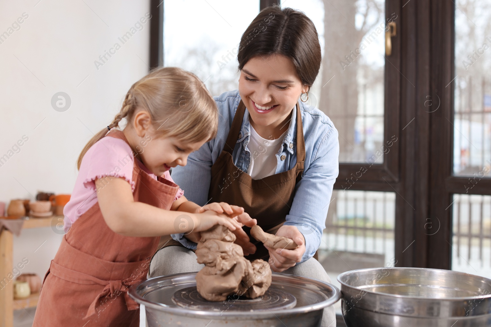 Photo of Hobby and craft. Smiling mother with her daughter making pottery indoors