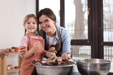 Photo of Hobby and craft. Smiling mother with her daughter making pottery indoors