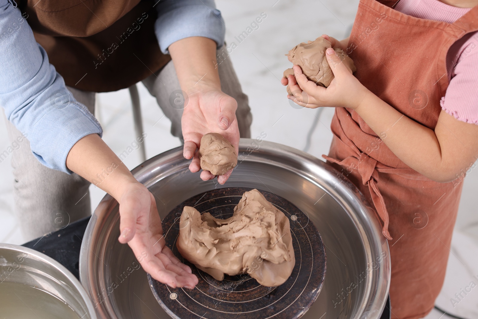 Photo of Hobby and craft. Mother with her daughter making pottery indoors, closeup