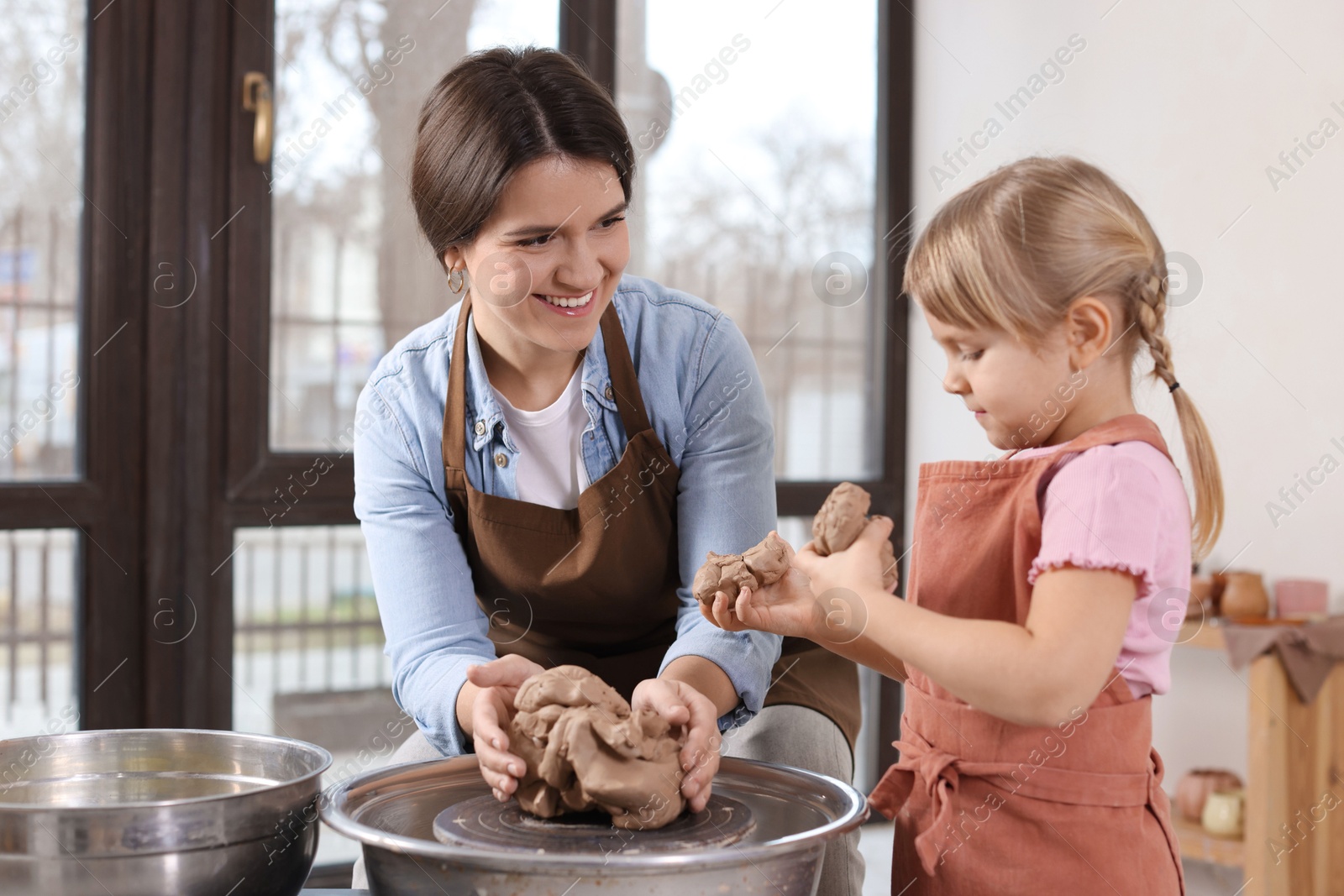 Photo of Hobby and craft. Smiling mother with her daughter making pottery indoors