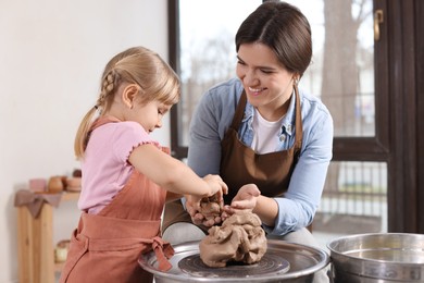 Photo of Hobby and craft. Smiling mother with her daughter making pottery indoors