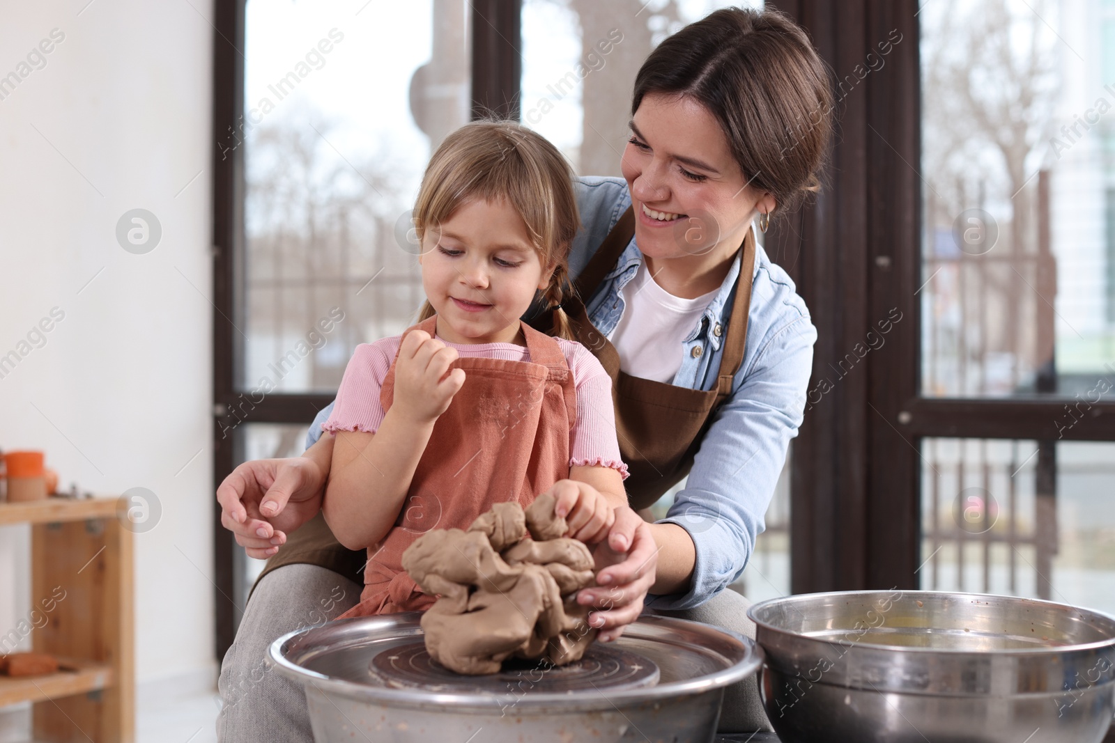 Photo of Hobby and craft. Smiling mother with her daughter making pottery indoors