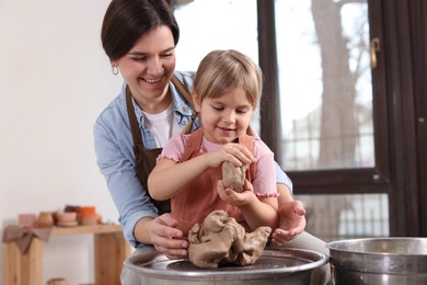 Photo of Hobby and craft. Smiling mother with her daughter making pottery indoors